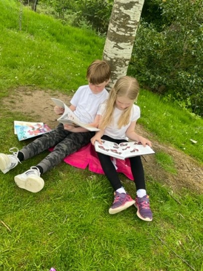 kids sitting on grass reading